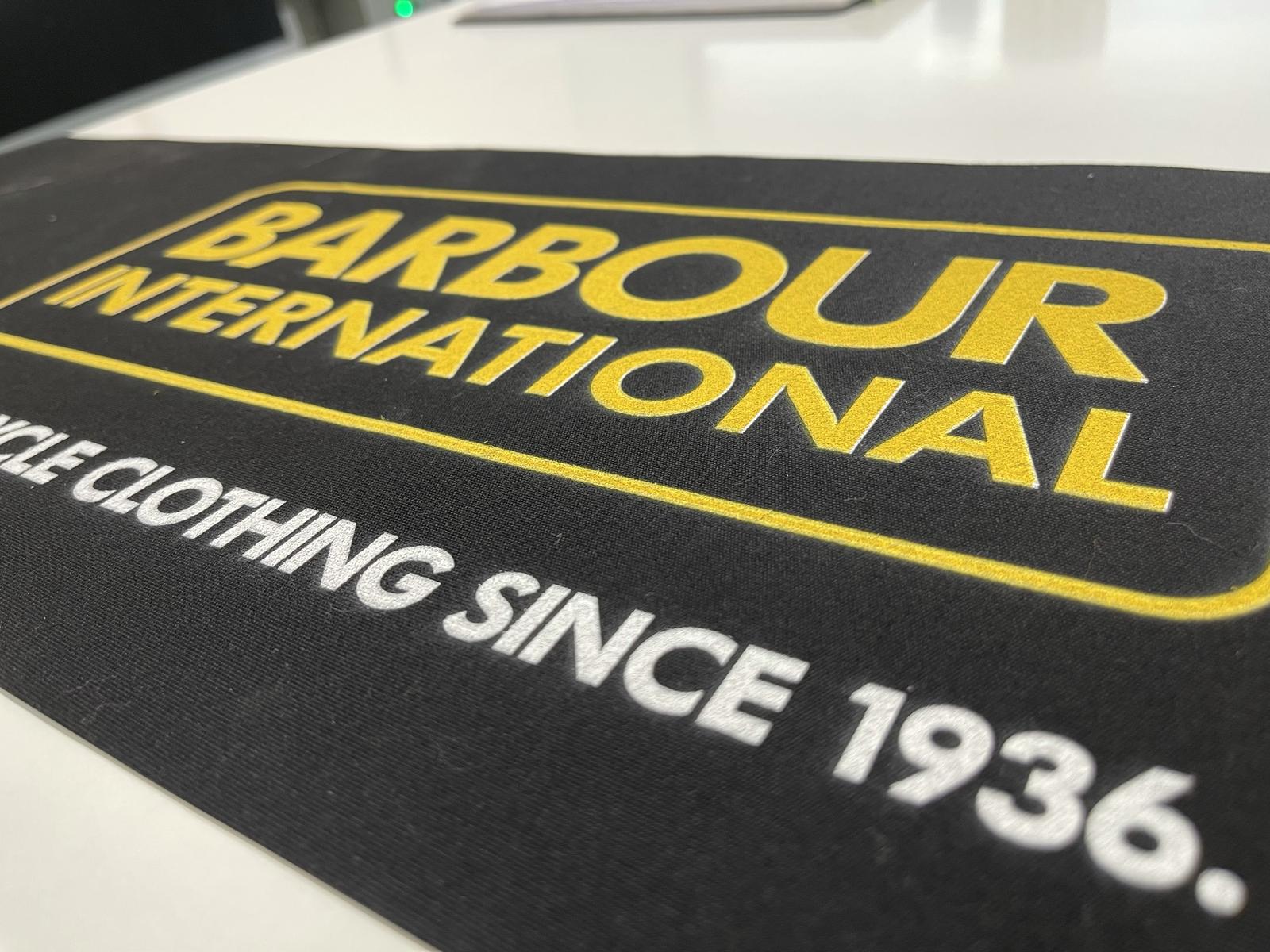 Marquage sur lambrequin : logo jaune et blanc floqué sur toile noire pour une marque de vêtements